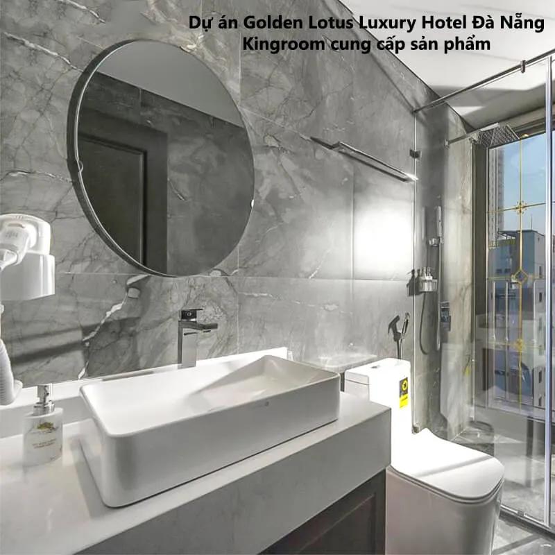 Phòng tắm với lavabo trắng và gương tròn tại Golden Lotus Luxury Hotel Đà Nẵng.