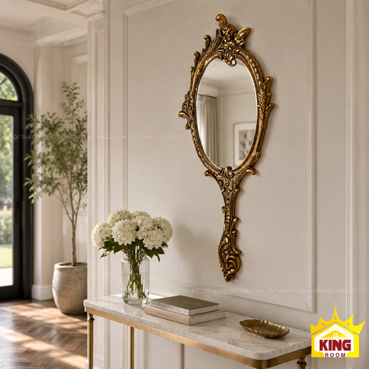 Gương oval cổ điển phía trên bàn console Gương oval khung vàng đồng treo trên bàn console mặt đá, bên bình hoa trắng