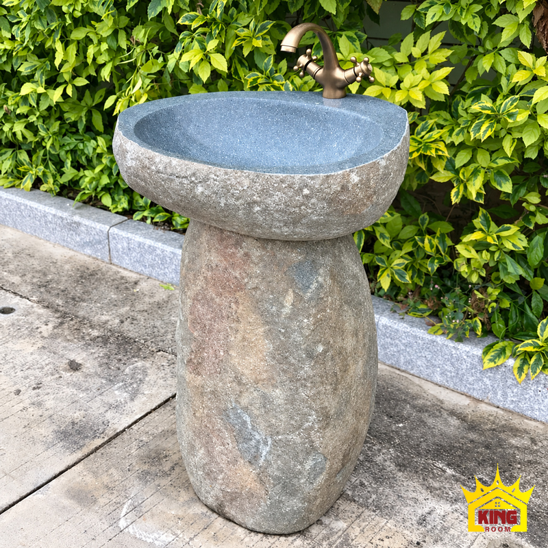 Chậu lavabo đá cuội tự nhiên chân đứng đế đá mộc, góc nghiêng thấy lòng xám xanh, chân đá cao có vân mộc và vòi màu đồng hai tay vặn