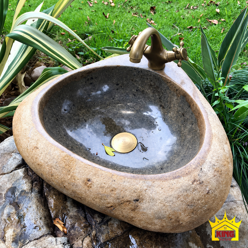 Chậu lavabo đá cuội tự nhiên dáng tam giác bo góc, góc nghiêng trên đá tự nhiên, vành tam giác bo góc, lòng xám sẫm và vòi vòm màu đồng phía sau