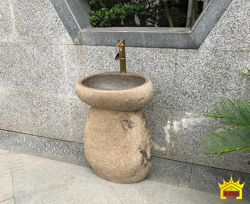 Lavabo đá cuội chân bầu – Bộ chậu chân bầu be đặt cạnh tường đá và cây xanh Bộ chậu chân bầu be đặt cạnh tường đá và cây xanh