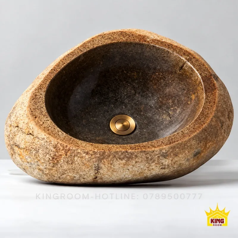 Chậu đá cuội thành be nâu nhìn từ trên với lòng sẫm và đầu xả tông đồng